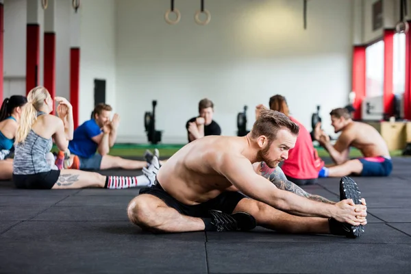 Beslutsamma instruktör tränar med klienter på golvet — Stockfoto