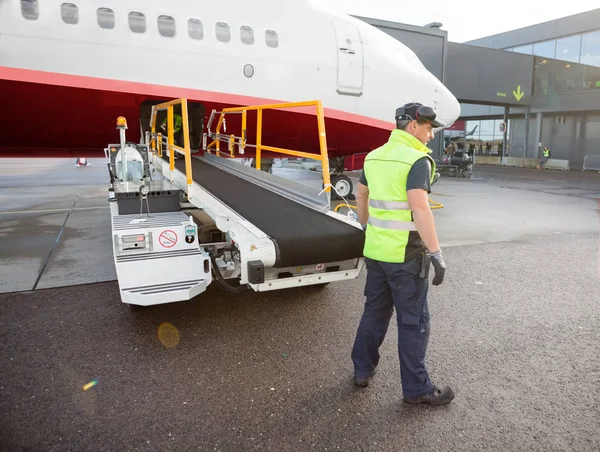 飛行機に接続されている荷物コンベアによって立っている労働者 — ストック写真