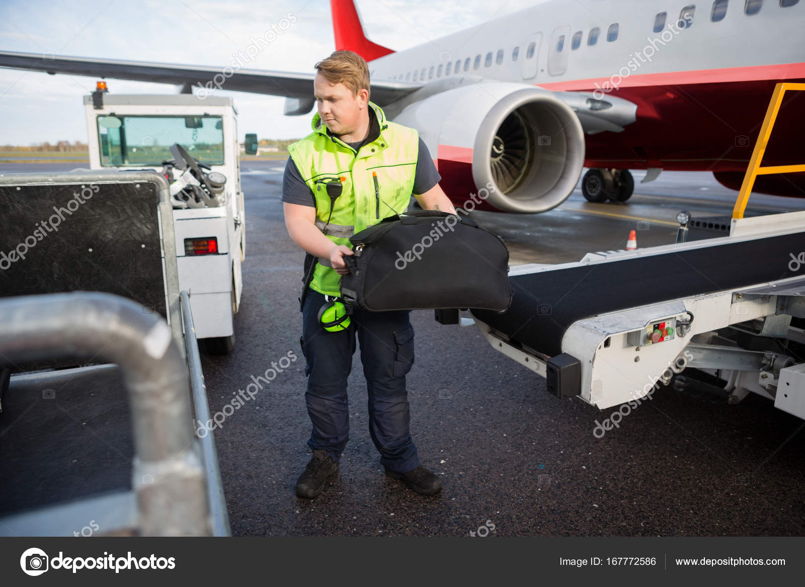 Worker Lifting Luggage From Conveyor Attached To Airplane Stock