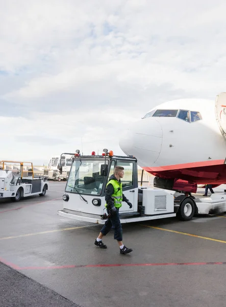 Trabajador caminando en camión remolcando avión en pista — Foto de Stock