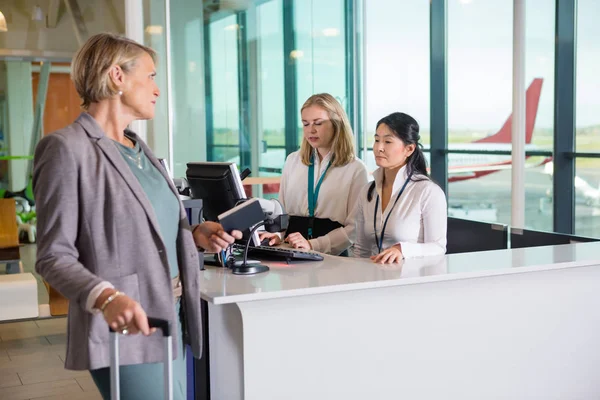 Havaalanında çalışan resepsiyonist bakarak karşı yolcu — Stok fotoğraf
