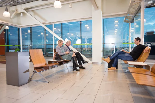 Pasajeros que esperan el vuelo en la terminal del aeropuerto — Foto de Stock