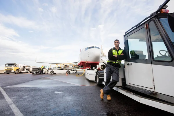 Trabalhador que se inclina no caminhão com avião no fundo — Fotografia de Stock