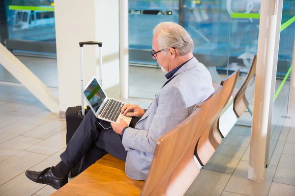 商人在机场航站楼使用笔记本电脑 — 图库照片