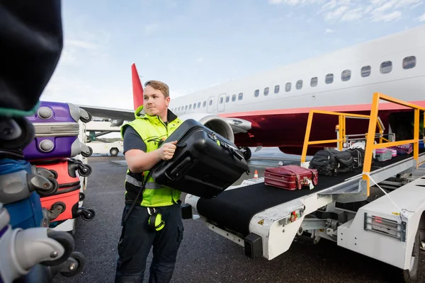 Працівник складає сумки на трейлері на злітно-посадковій смузі — стокове фото