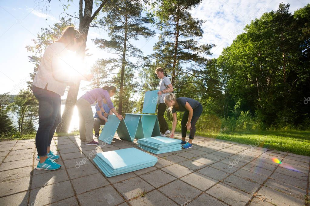 Friends Making Wooden Plank Pyramid On Patio In Forest