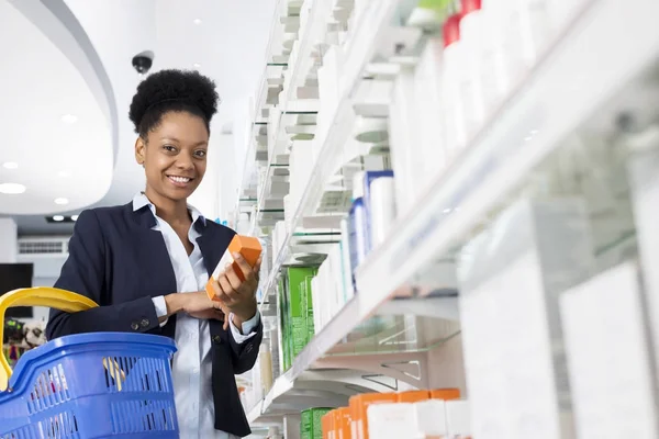 Empresaria sosteniendo medicina por estantes en farmacia —  Fotos de Stock