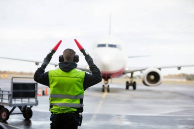 Ground Crew Signaling To Airplane On Wet Runway clipart