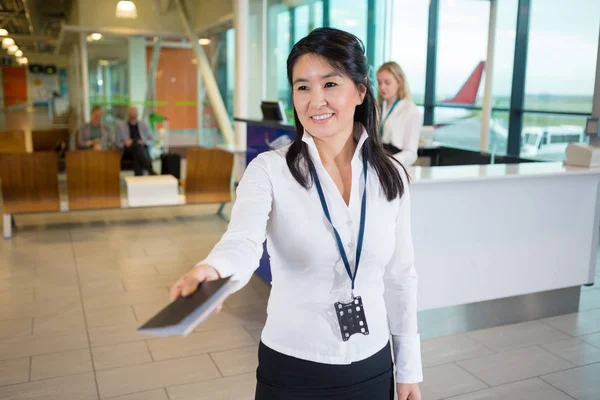 Membro do pessoal sorrindo dando passaporte no terminal do aeroporto — Fotografia de Stock