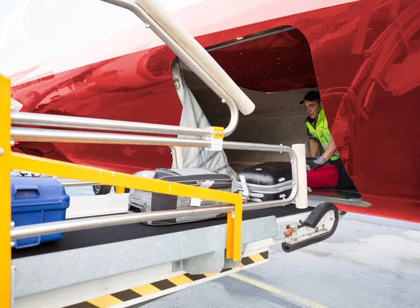 Travailleur plaçant des bagages sur le convoyeur lors du déchargement de l'avion — Photo