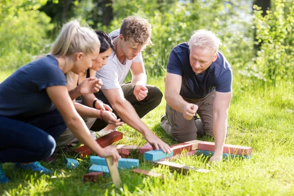 Vrienden plannen terwijl stapelen bouwstenen op gras veld — Stockfoto