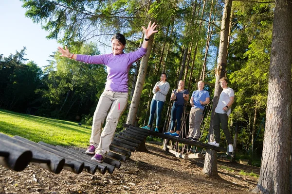 Amigos Mujer motivadora cruzando el puente de troncos en el bosque — Foto de Stock