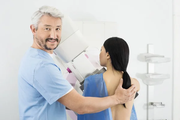 Porträt eines Arztes, der einer Frau beim Röntgen des Mammogramms hilft — Stockfoto