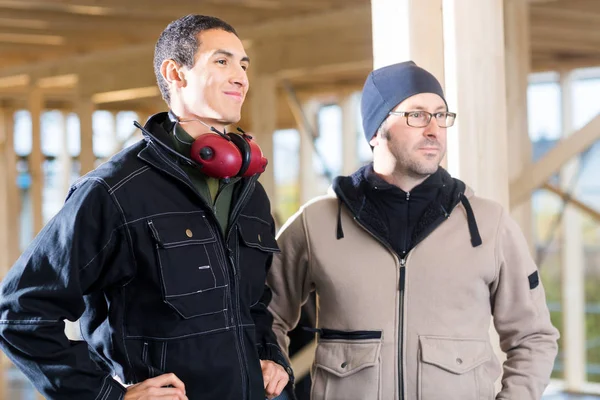Carpenters In Jackets Looking Away While Standing At Site — Stock Photo, Image