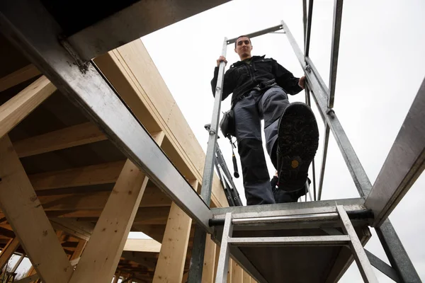 Masculino carpinteiro movendo-se para baixo escada de incompleto edifício — Fotografia de Stock