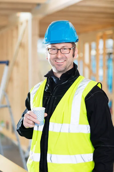 Carpinteiro segurando xícara de café no canteiro de obras — Fotografia de Stock