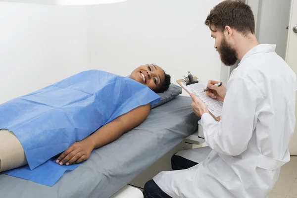 Paciente feminina deitada na cama enquanto o médico segurava a área de transferência — Fotografia de Stock