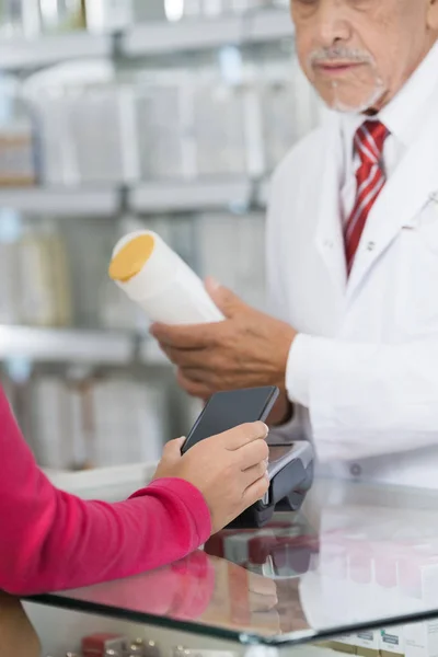 Vrouw maken van Nfc betaling terwijl scheikundige bedrijf Shampoo fles — Stockfoto