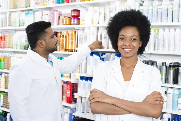 Farmacista in piedi braccia incrociate mentre il collega di organizzare Produ — Foto Stock