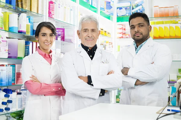 Farmacéuticos multiétnicos armados cruzados en farmacia — Foto de Stock