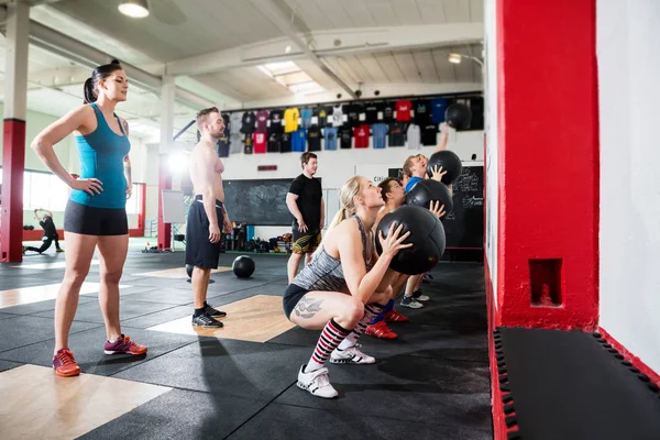 Trainers kijken naar Clients geneeskunde ballen gooien op muur — Stockfoto