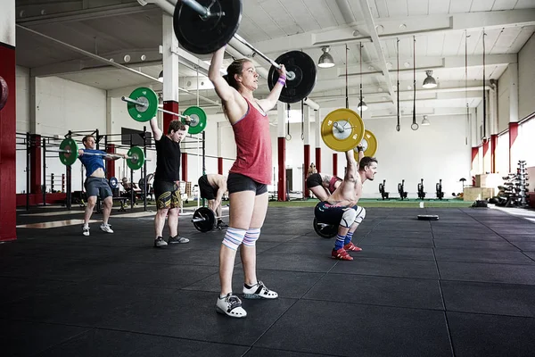 Atletas levantando barras en el gimnasio — Foto de Stock