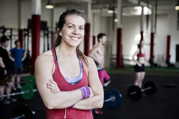 Donna in forma con le braccia incrociate in piedi nel centro fitness — Foto Stock