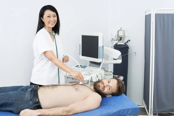 Médico feliz realizando o teste de ultra-som no paciente — Fotografia de Stock