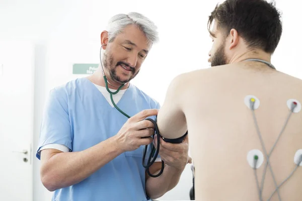 Médico que mede a pressão arterial do paciente no hospital — Fotografia de Stock