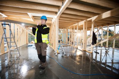 Omuz otur, tahta taşıyan koruyucu ceketli bir marangoz