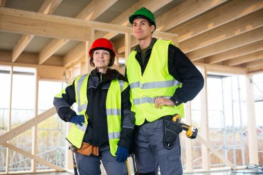 Kendine güvenen marangozlar inşaat sahasında yansıtıcı ceketler