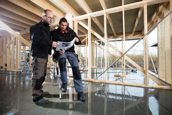 Carpenters Analyzing Plan At Construction Site — Stock Photo, Image
