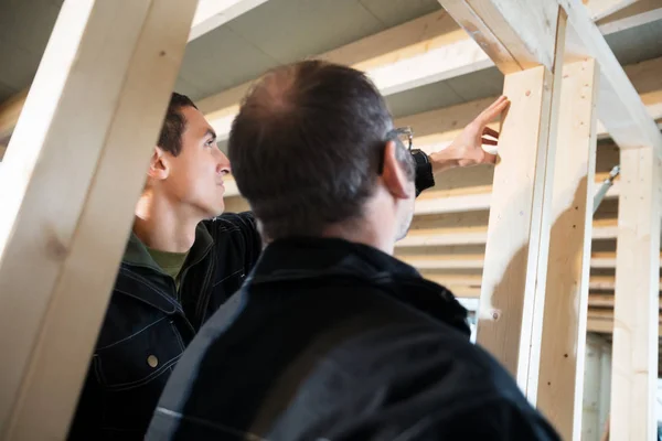 Vista de ángulo bajo de carpinteros analizando madera en Buildi incompleto — Foto de Stock