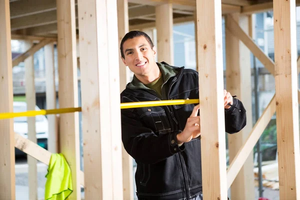 Jeune menuisier mesurant le bois sur le chantier — Photo