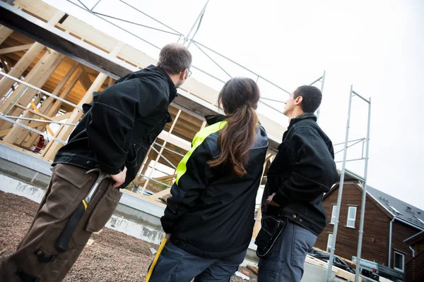 Charpentier féminin debout près de collègues sur le chantier de construction — Photo