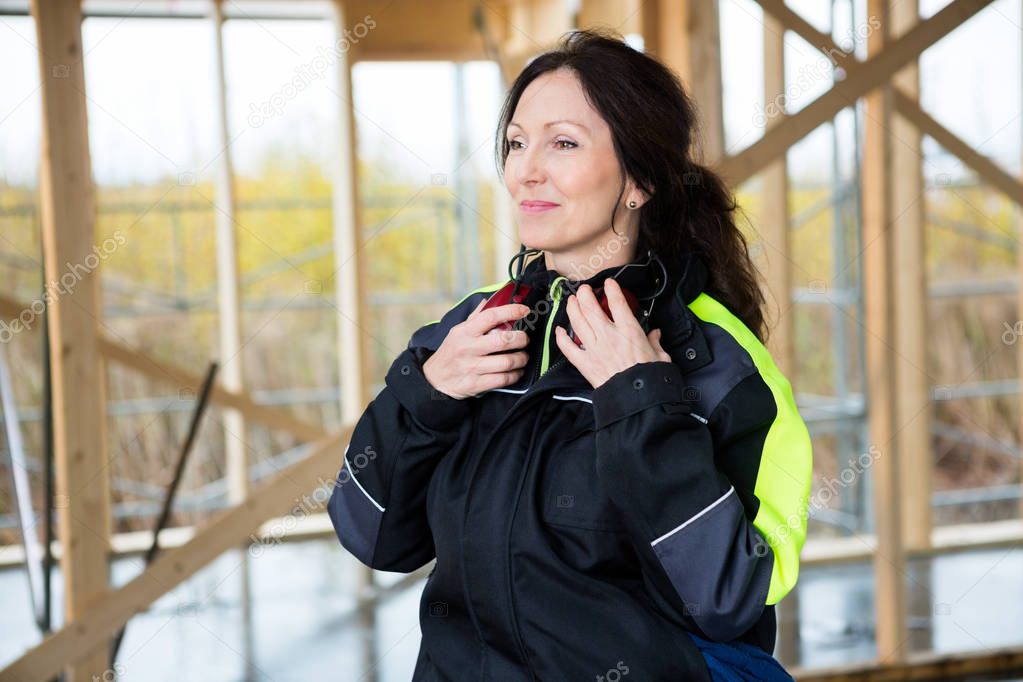 Female Carpenter With Ear Protectors At Site