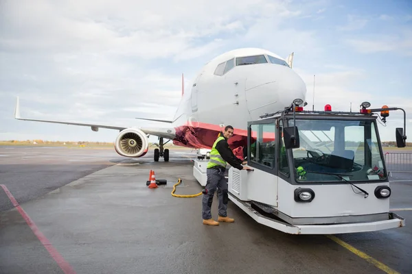 Caminhão de reboque de abertura do trabalhador anexado ao avião — Fotografia de Stock
