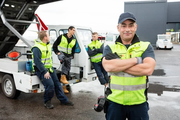 Matura lavoratore in piedi braccia incrociate mentre i colleghi Communicati — Foto Stock