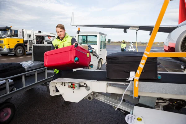 Разгрузка багажа с конвейера, прикрепленного к самолету — стоковое фото