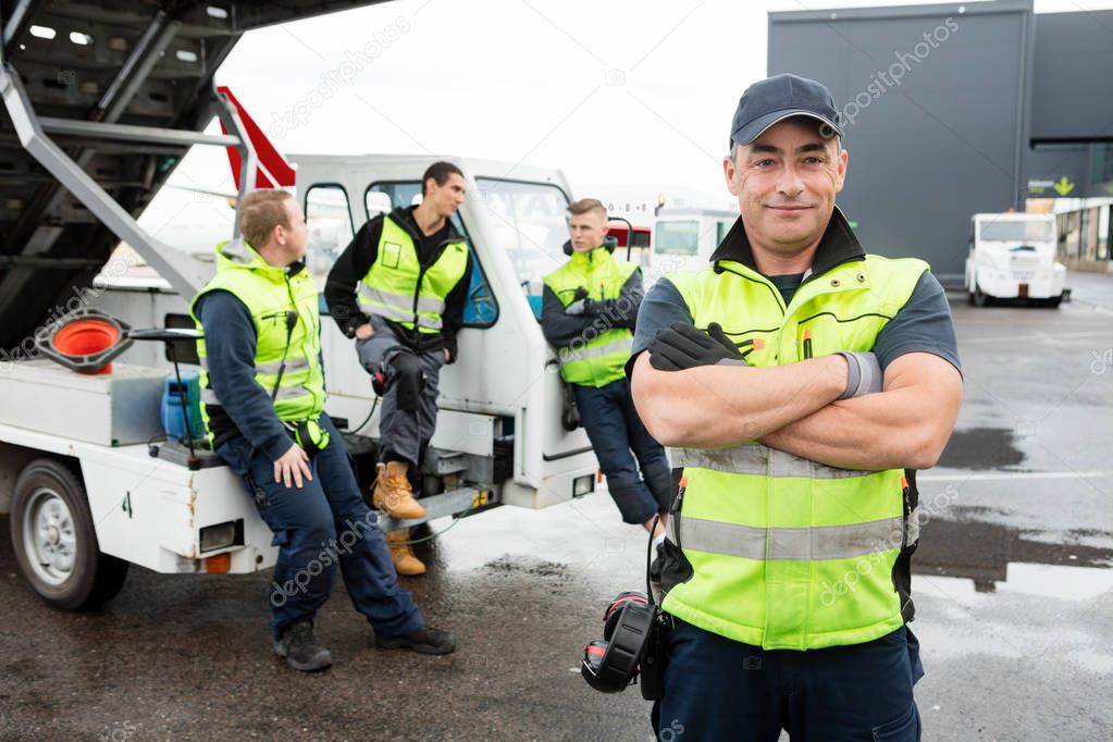 Mature Worker Standing Arms Crossed While Colleagues Communicati