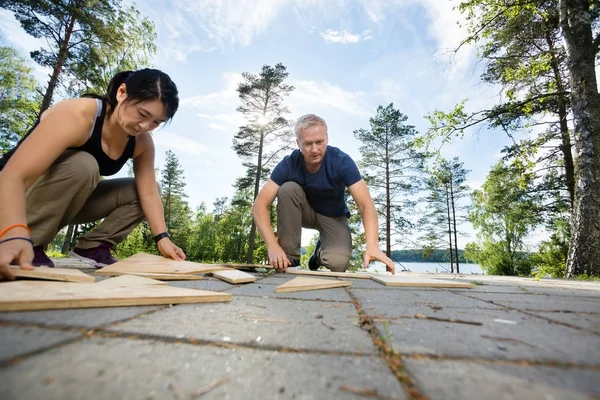 Amigos resolviendo rompecabezas con tablones de madera en el patio —  Fotos de Stock