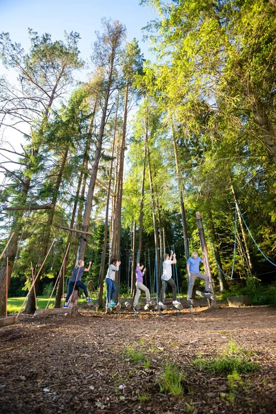 Multiétnicos amigos cruzando balançando logs na floresta — Fotografia de Stock