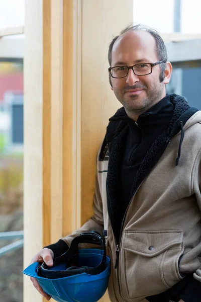 Självsäker mogen snickare hålla Hardhat på plats — Stockfoto