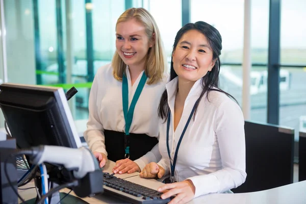 Recepcionistas sonrientes sentados en el mostrador de ayuda en el aeropuerto — Foto de Stock