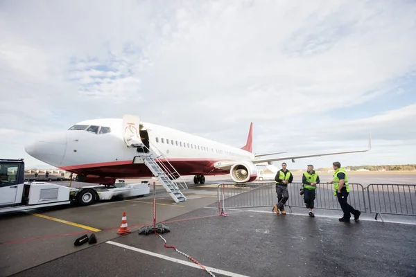 Tripulación apoyada en valla mientras está de pie junto al avión —  Fotos de Stock
