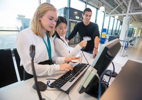 Recepcjonistka w paszport przy użyciu komputera, podczas gdy kolega Scanni — Zdjęcie stockowe