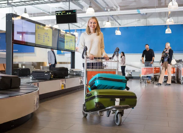 Ung kvinna med bagage i vagn på flygplats — Stockfoto