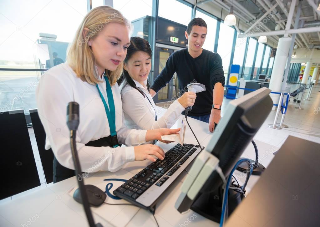 Receptionist With Passport Using Computer While Colleague Scanni