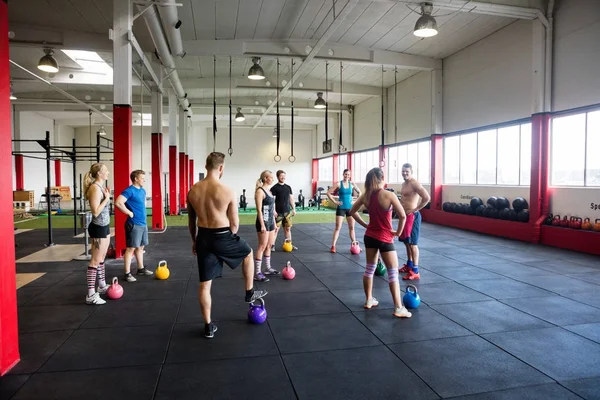 Hombres y mujeres con pesas de pie en el gimnasio — Foto de Stock