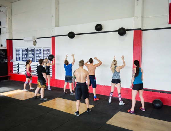 Men And Women Throwing Medicine Balls On Wall Royalty Free Stock Images